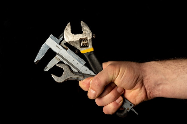 La mano del maestro sostiene un conjunto de herramientas para reparar tuberías.