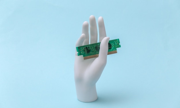 Mano de maniquí blanco sujetando el chip de computadora y se encuentra sobre fondo azul.