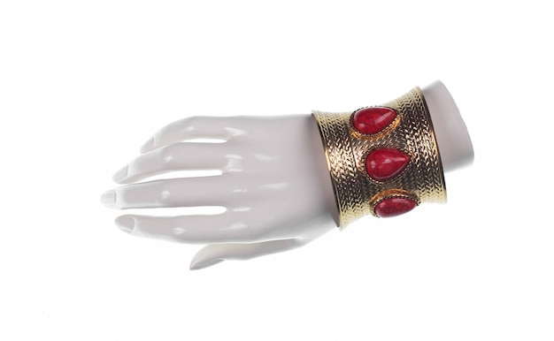 Mano de maniquí con brazalete de joyería aislado sobre fondo blanco.