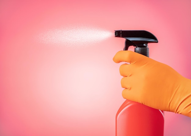 Mano a mano sostiene un spray de líquido de limpieza sobre un fondo rosa con espacio de copia Concepto de servicio de limpieza