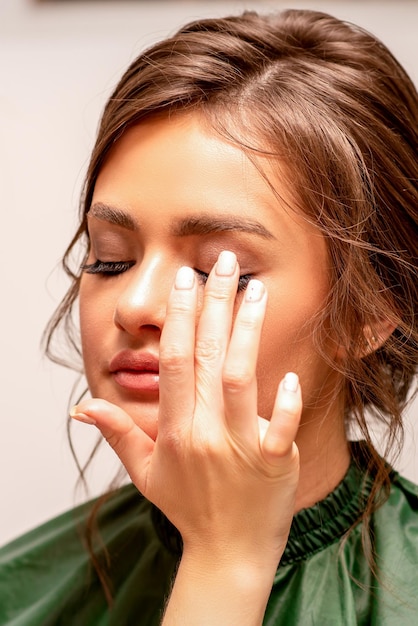 La mano de un maquillador aplica sombra de ojos en el párpado de una joven caucásica