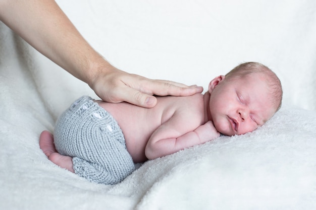 La mano más gorda con el bebé recién nacido duerme los primeros días de vida. Lindo niño recién nacido durmiendo pacíficamente