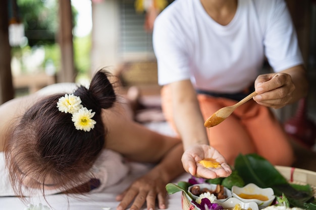 La mano de la masajista usa miel para masajes y tratamientos relajantes de spa del síndrome de la oficina estilo tradicional de masaje tailandés