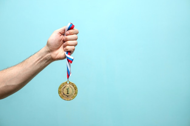 la mano masculina del atleta ganador tiene la medalla de oro