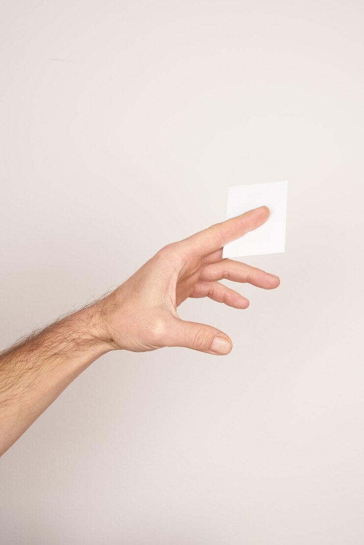 Foto mano masculina blanca dando una tarjeta de visita en blanco sobre un fondo blanco aislado.