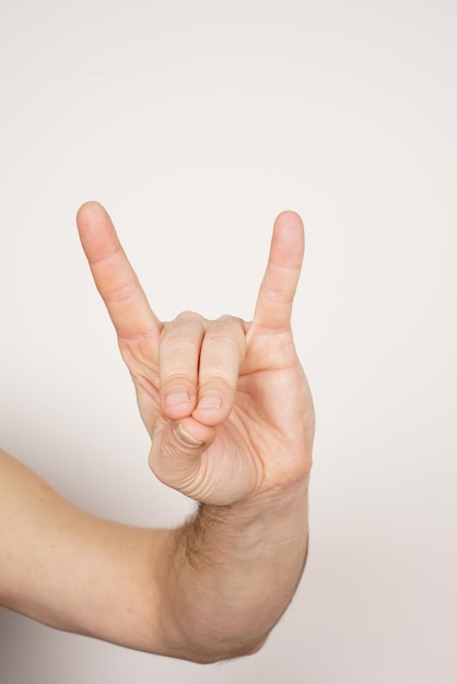 Mano masculina blanca que muestra el signo de la mano del lobo sobre fondo blanco aislado.