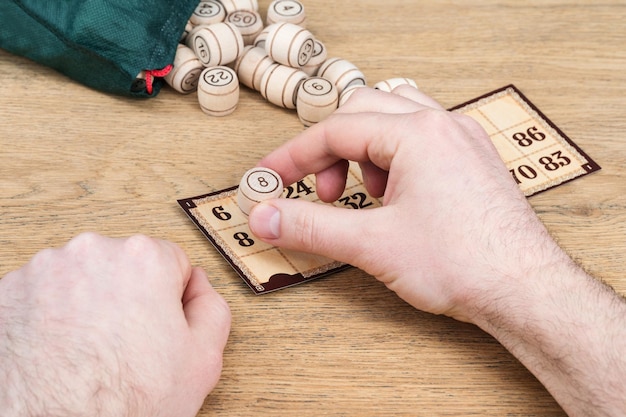 Mano masculina cierra la figura con ocho barriles de madera en un juego de lotería