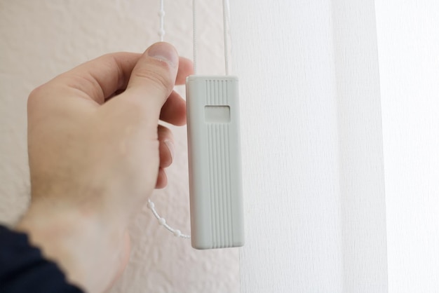 La mano masculina cierra las persianas de la ventana de la luz del sol