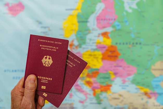 Mano masculina con dos pasaportes alemanes sobre el mapa de europa