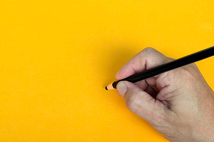 Foto mano masculina escribe con lápiz negro sobre un fondo amarillo copiar espacio concepto de enseñanza
