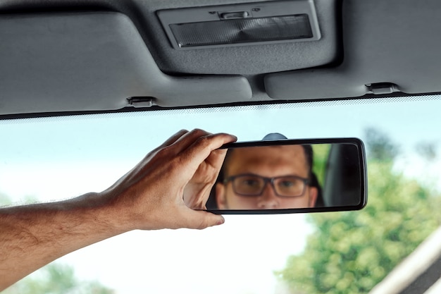Mano masculina en el espejo retrovisor de un automóvil