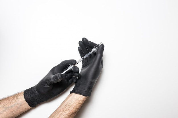 Foto mano masculina en un guante médico con una vacuna en una pared blanca