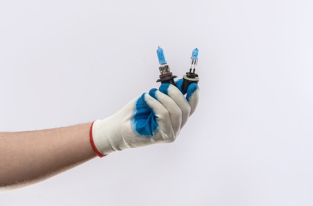 Mano masculina en guantes sosteniendo bombillas de un coche para faros aislados, equipo automático