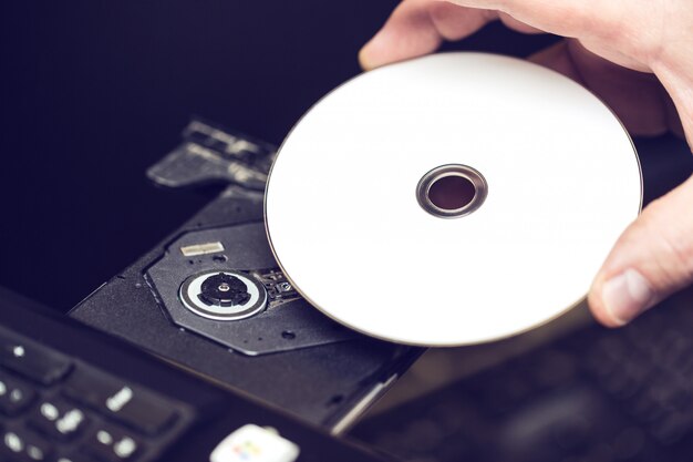 Mano masculina insertando un DVD en una unidad de disco