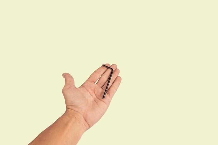 Foto mano masculina negra ofreciendo una llave allen aislada en un fondo verde claro
