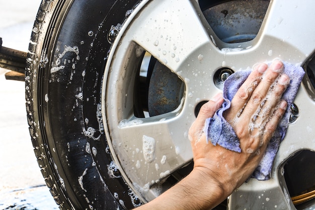 Mano masculina con paño azul lavado rueda coche