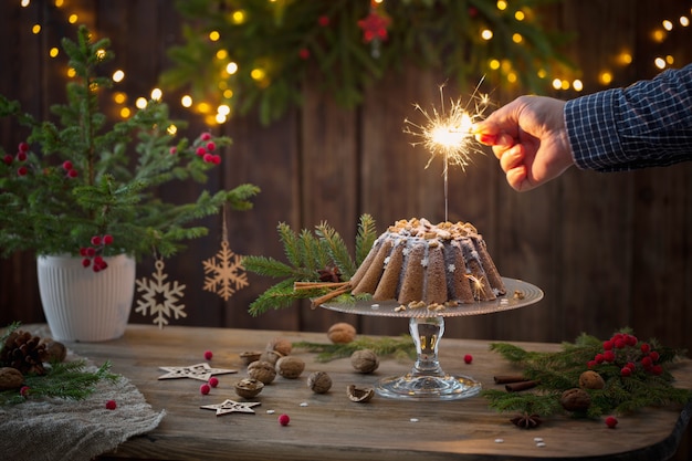 Mano masculina prende fuego a bengala en pastel de navidad