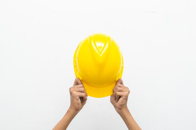 Foto mano masculina que sostiene el casco de seguridad amarillo aislado sobre fondo blanco. concepto de seguridad laboral.