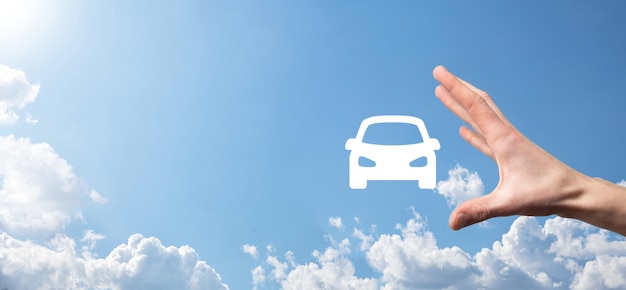Mano masculina que sostiene el icono del auto del coche en fondo azul. Amplia composición de pancartas. Seguro de automóvil y conceptos de exención de daños por colisión.