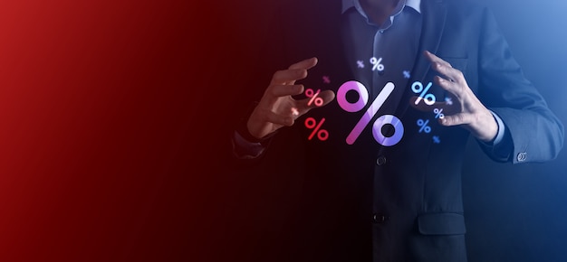 Mano masculina que sostiene el icono de porcentaje de tasa de interés sobre fondo azul. Concepto de tasas de interés financieras e hipotecarias.Banner con espacio de copia