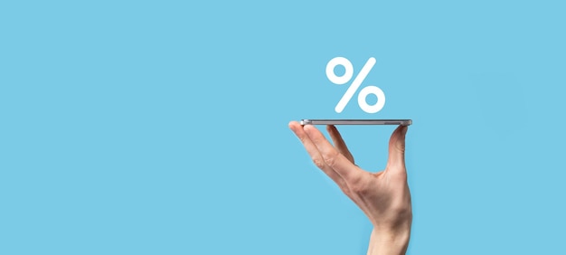 Foto mano masculina que sostiene el icono de porcentaje de tasa de interés sobre fondo azul. concepto de tasas de interés financieras e hipotecarias. banner con espacio de copia.