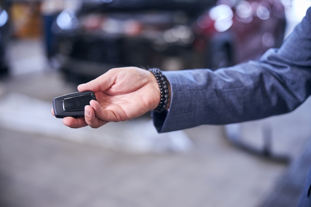 Mano masculina que sostiene la llave del coche electrónico moderno