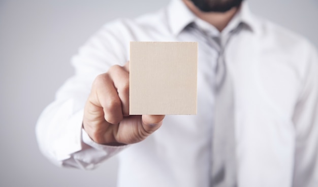 Mano masculina que sostiene el tablero vacío de madera para su texto.