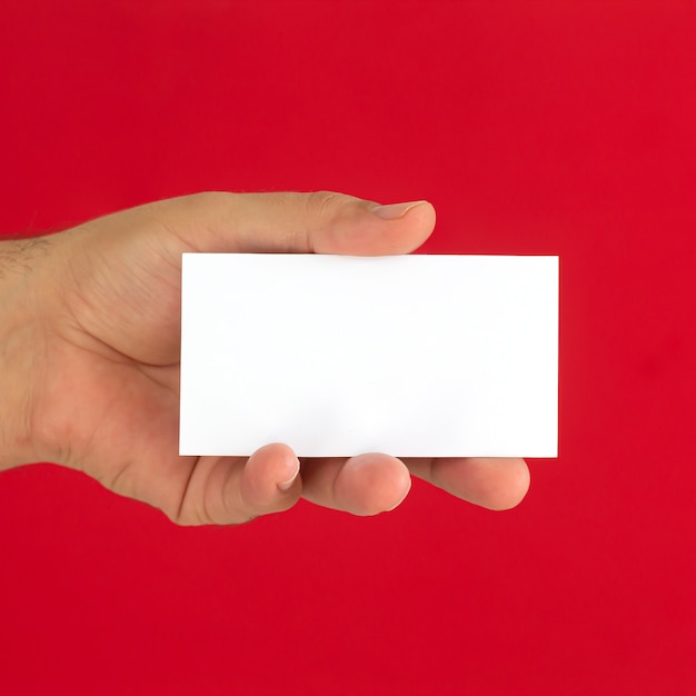 Mano masculina que sostiene la tarjeta de visita en blanco sobre fondo rojo.