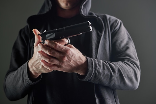 Foto mano masculina sosteniendo un arma sobre fondo negro un arma en la mano de un hombre defensa o ataque asesino o ladrón armado vista en primera persona de una pistola