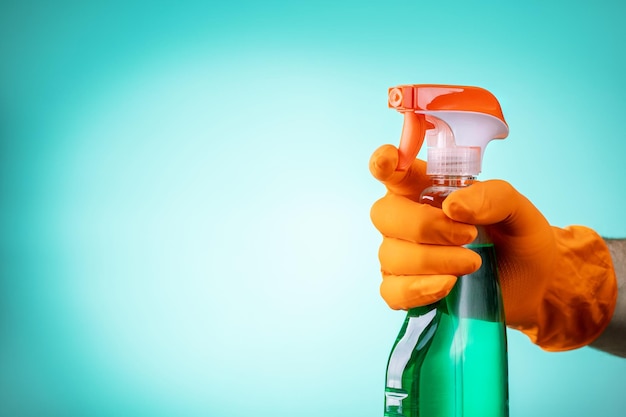 Mano masculina sosteniendo botella de spray sobre fondo de menta Concepto de servicio de limpieza