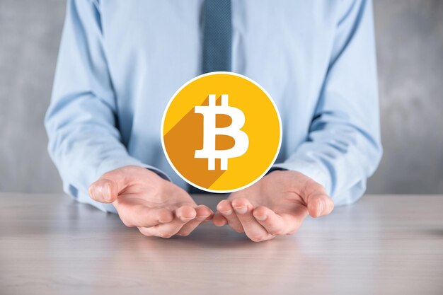 Mano masculina sosteniendo un icono de bitcoin sobre fondo gris Bitcoin Cryptocurrency Digital Bit Coin BTC Moneda Tecnología Negocio Internet Concepto