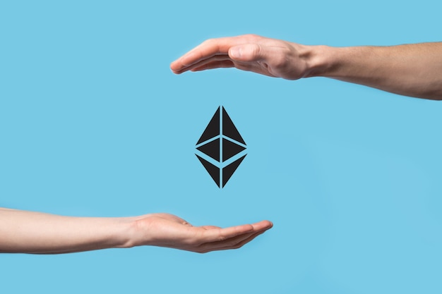 Mano masculina sosteniendo un icono de Ethereum sobre fondo azul. Concepto de inversión de Ethereum y criptomonedas. intercambio, comercio, transferencia e inversión de tecnología blockchain.