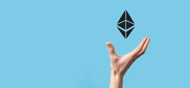Mano masculina sosteniendo un símbolo Ethereum sobre fondo azul. Concepto de inversión de Ethereum y criptomonedas. intercambio, comercio, transferencia e inversión de tecnología blockchain.