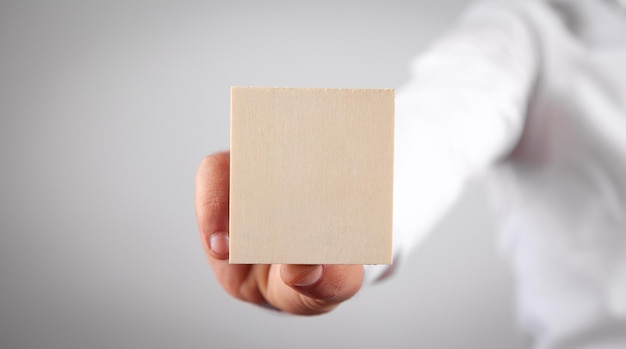 Mano masculina sosteniendo una tabla vacía de madera para tu texto