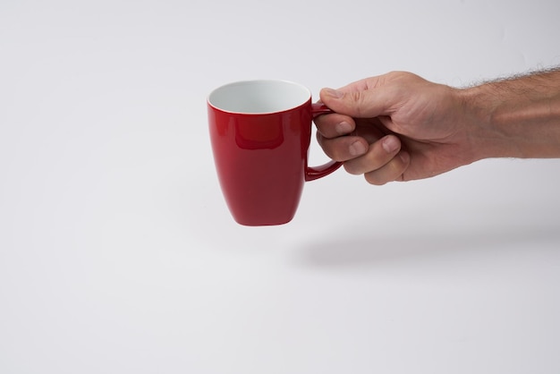 Mano masculina sosteniendo una taza de café roja