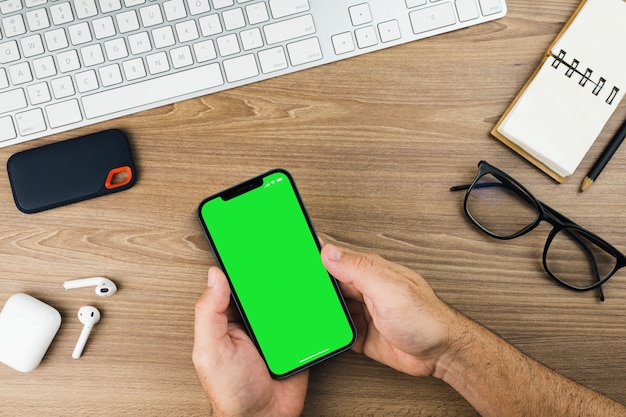 Mano masculina sosteniendo un teléfono inteligente con Chroma Key en la pantalla. Pantalla verde.