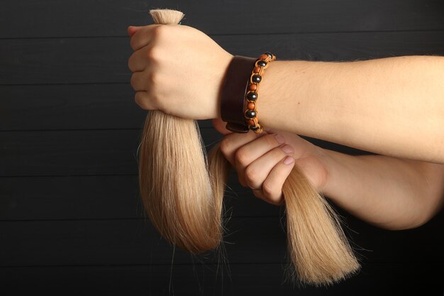 La mano masculina sostiene secciones de cabello para extensión.