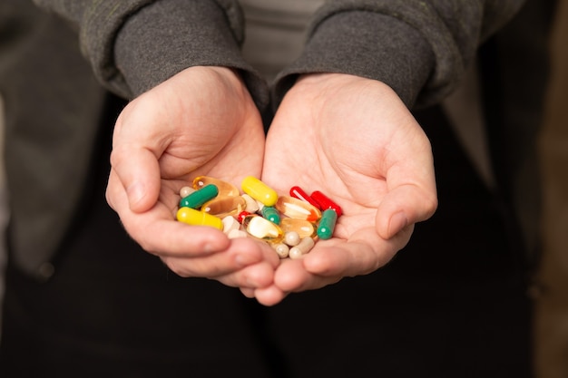 Mano masculina con varias pastillas y suplementos diarios para una vida sana