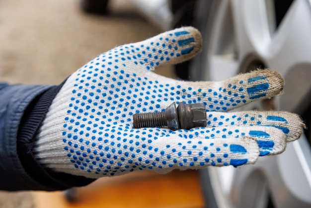 Mano mecánica en guante de tela con perno de rueda de coche