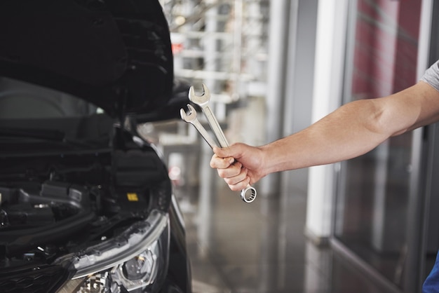 Mano de mecánico de automóviles con llave. Garaje de reparación de automóviles.