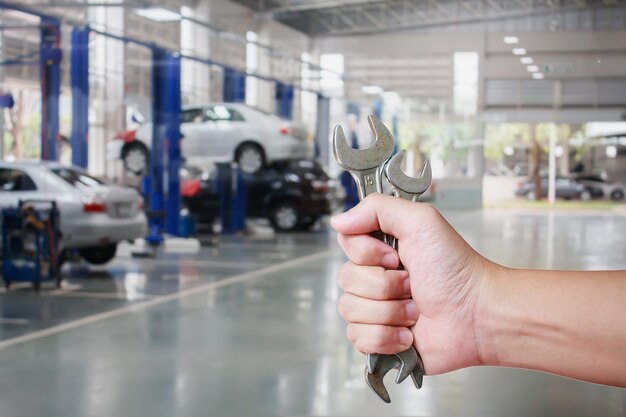 Mano de mecánico de automóviles profesional con llave