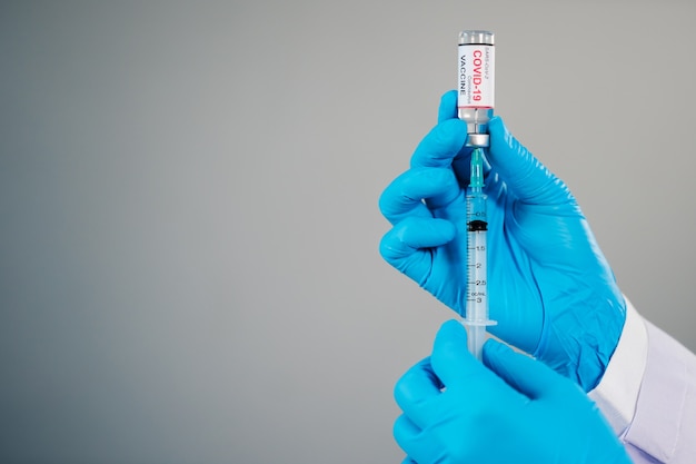 Mano del médico dibujando una botella de vacuna de Coronavirus (Covid-19) en un medicamento de inyección de jeringa