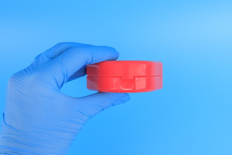 Foto la mano de un médico en un guante azul contiene una caja para el entrenador miofuncional para la corrección de los dientes.