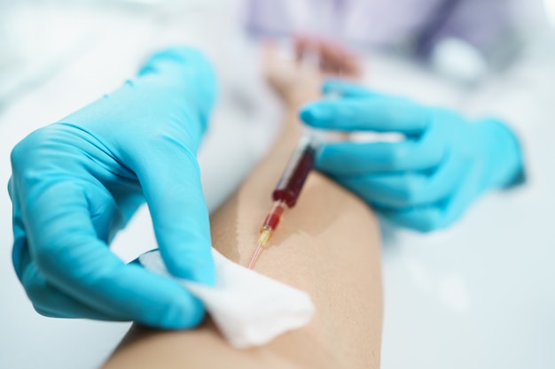 Mano del médico en guantes azules tomando muestras de sangre de un paciente.