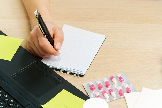 Mano del médico haciendo prescripción médica en el bloc de notas