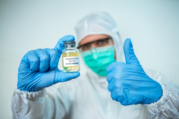 Mano de médico masculino apuntando con un coronavirus vial de vacuna