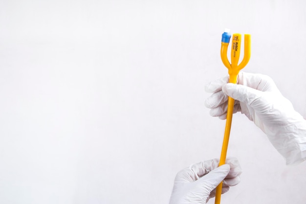 mano del médico sosteniendo un tubo de catéter de 3 vías de fiebre naranja, concepto de atención médica, adecuado para carteles.