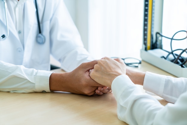 Mano del médico tranquilizar a su paciente femenino