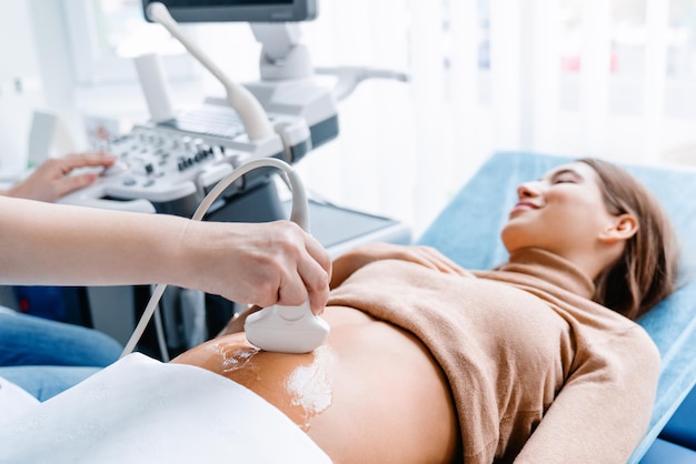 Mano del médico con ultrasonido durante el examen de ultrasonido de la paciente embarazada