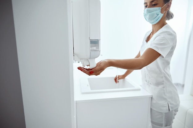 Mano del médico usando gel de lavado con alcohol para limpiar el dispensador de bomba de gel desinfectante Botella de gel desinfectante para manos concepto de cuidado de la salud